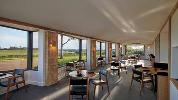 A spacious dining area with large windows, wooden furniture, and a view of the countryside.
