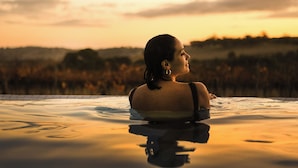 Una persona en un jacuzzi con vistas al atardecer.