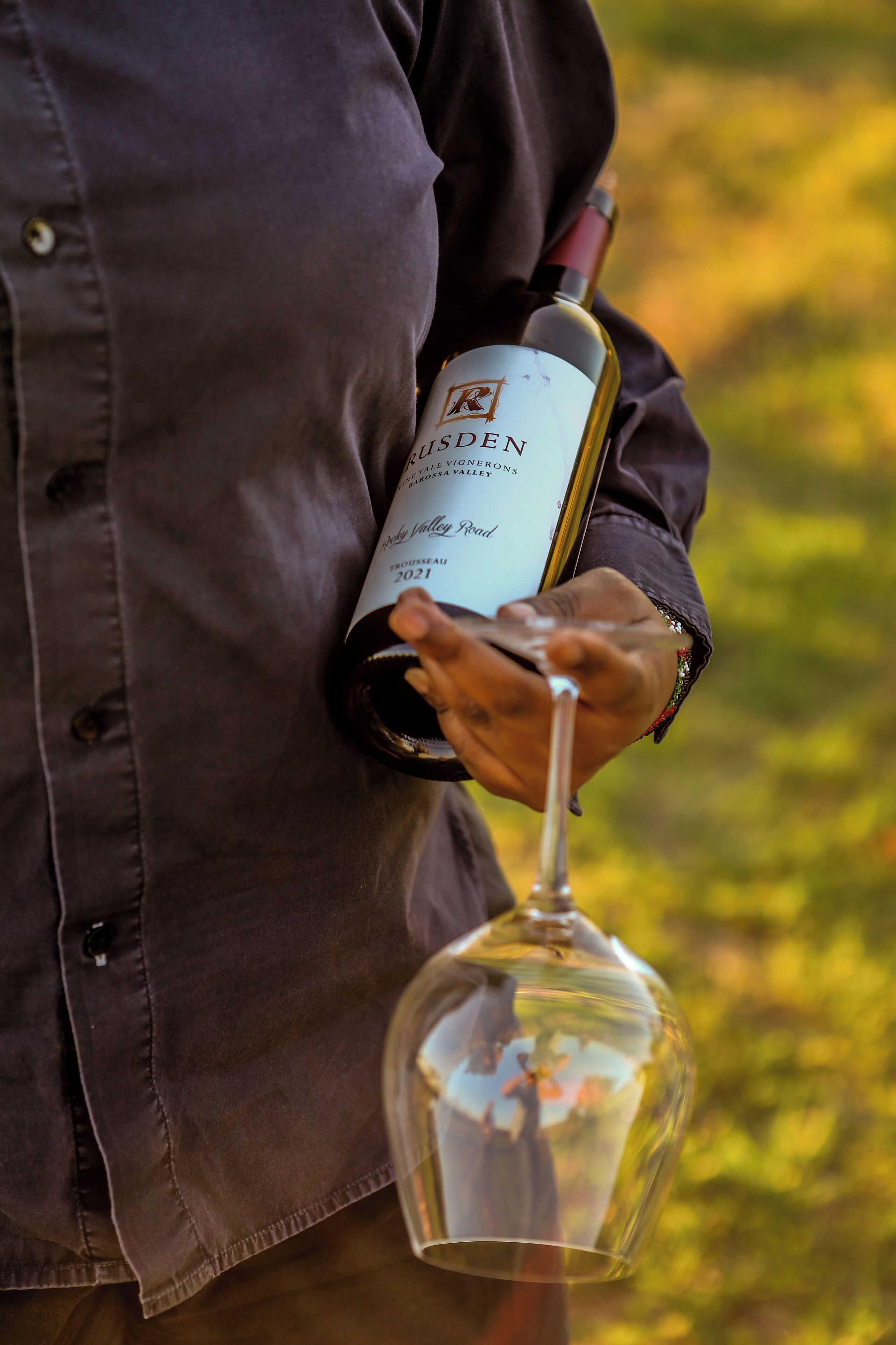 Uma pessoa segurando uma garrafa de vinho e uma taça de vinho.