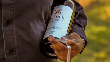 A person holding a bottle of wine and a wine glass.