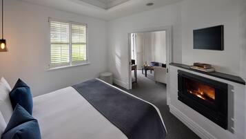 Ein modernes Hotelzimmer mit einem großen Bett, einem Kamin, einem an der Wand montierten Fernseher und einem Schreibtisch mit Stuhl.