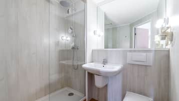 A modern bathroom with a glass-enclosed shower, a white sink, and a toilet.