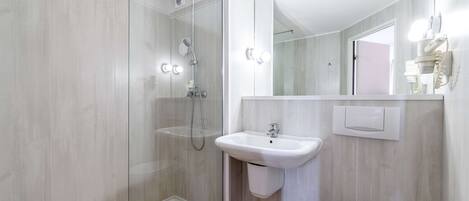 Un baño moderno con ducha de vidrio, lavamanos blanco y retrete.
