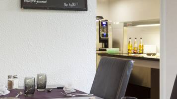 Un restaurante con un menú en la pared, una mesa preparada con cubiertos, vasos y servilleta.