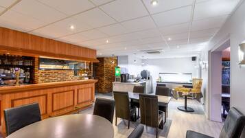 A modern restaurant with a bar area, seating, and a kitchen in the background.