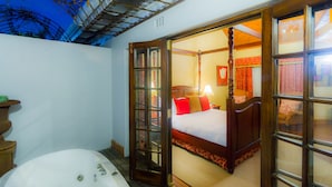 Un dormitorio con cama con dosel, un ventanal grande y un baño independiente con bañera.