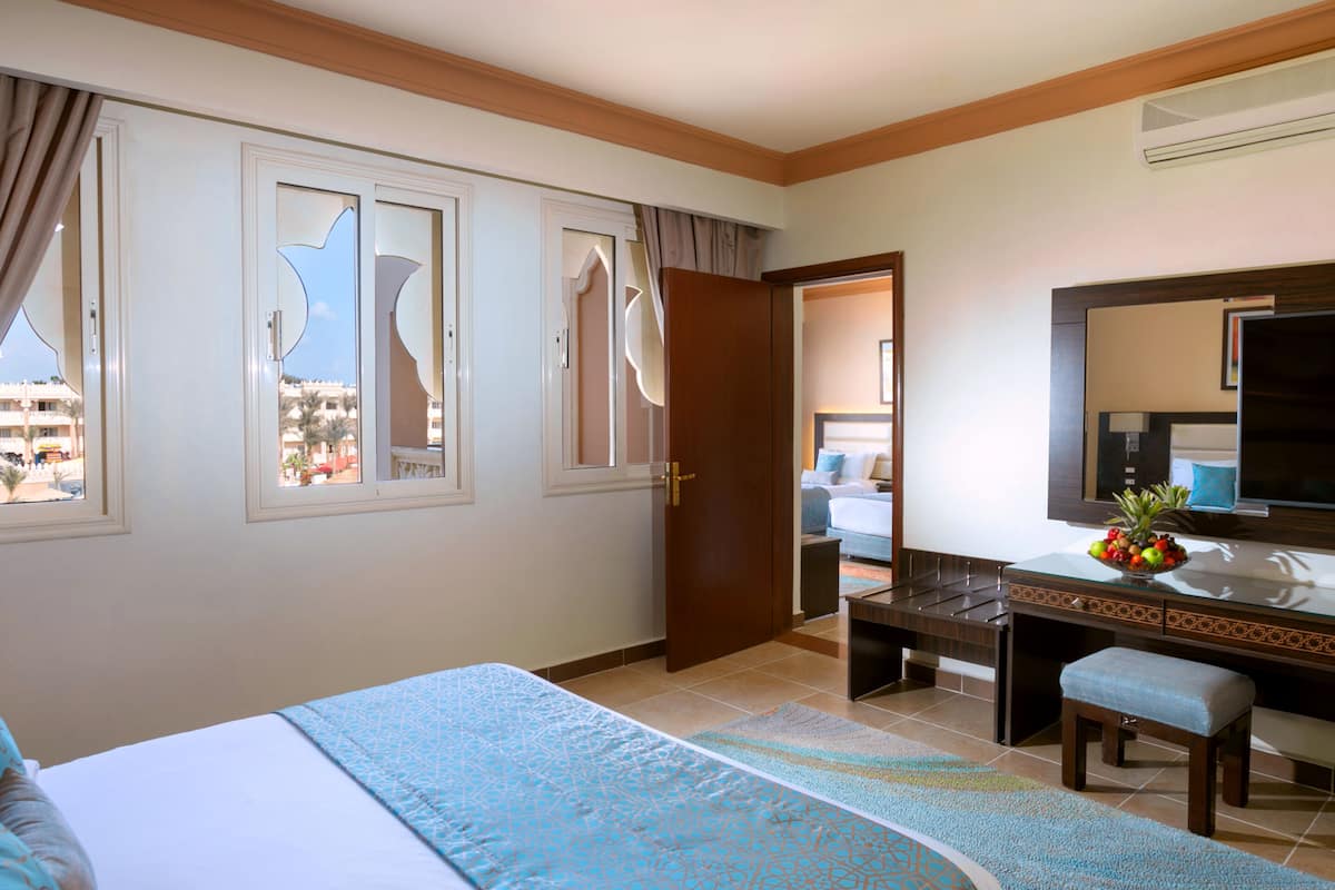 A hotel room with a bed, a desk, a chair, a television, and a window with a view of buildings.