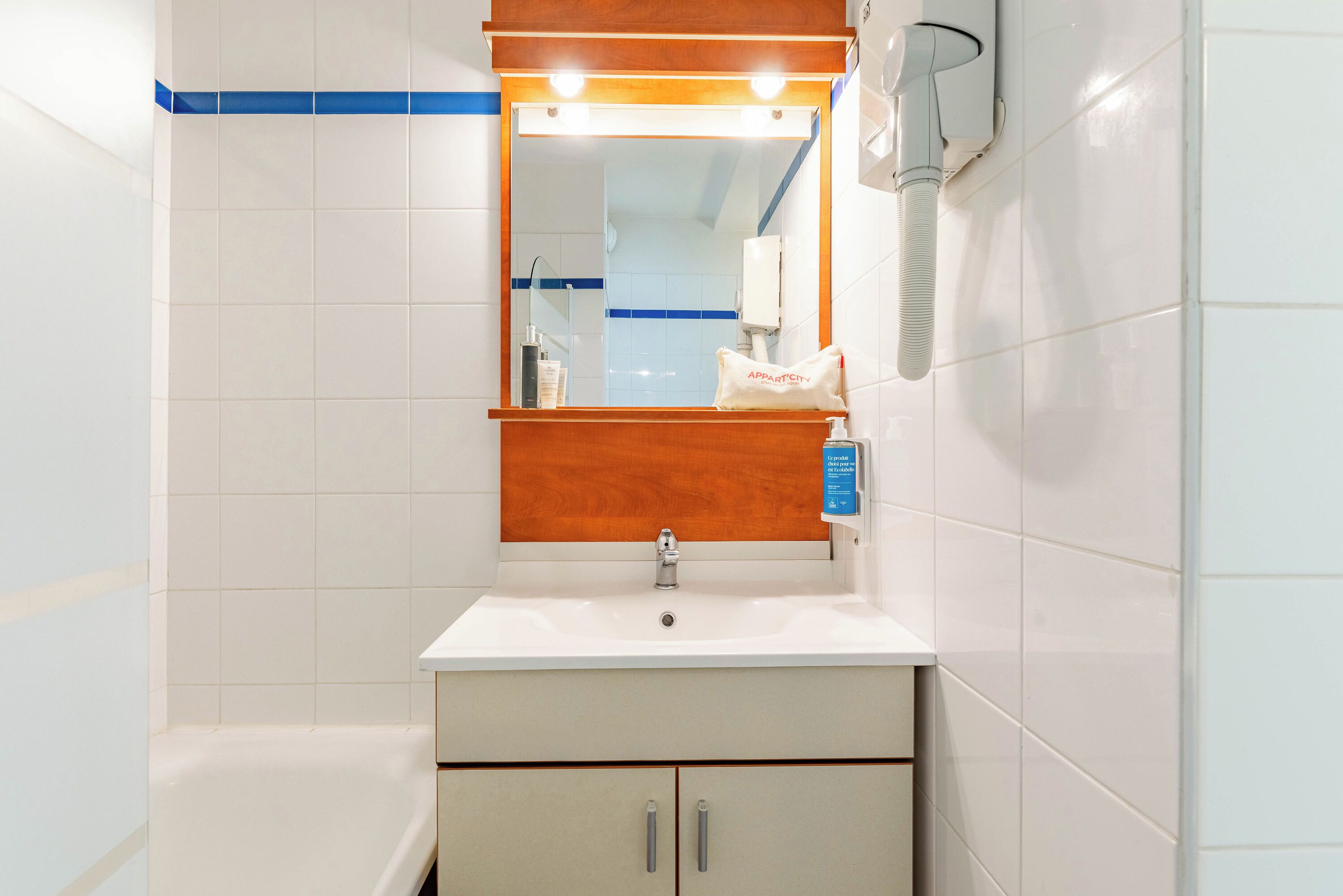Un baño con un lavamanos blanco, un espejo y una toalla colgada en la pared.