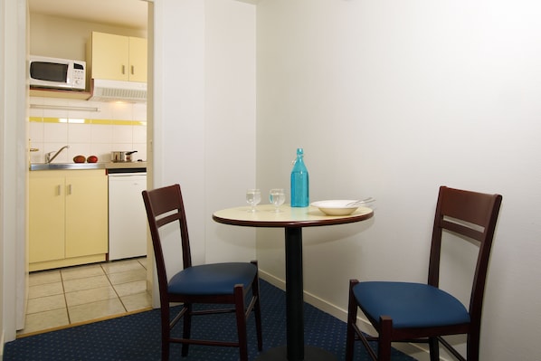 A small dining area with two chairs, a table, a microwave, and a sink in the background.