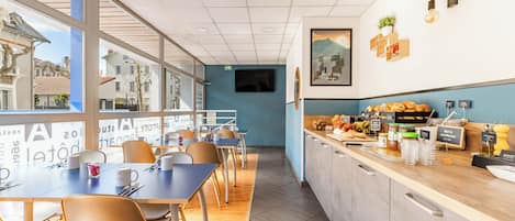 A modern cafe with a long counter, seating area, and large windows.