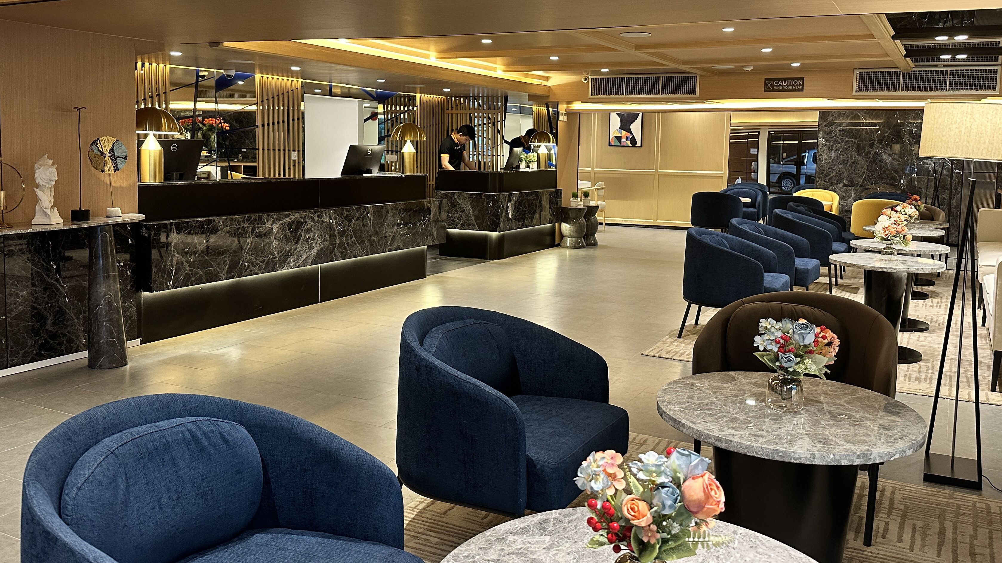 Un hall d’hôtel comprenant un comptoir d’accueil, un espace salon et un bar à café.