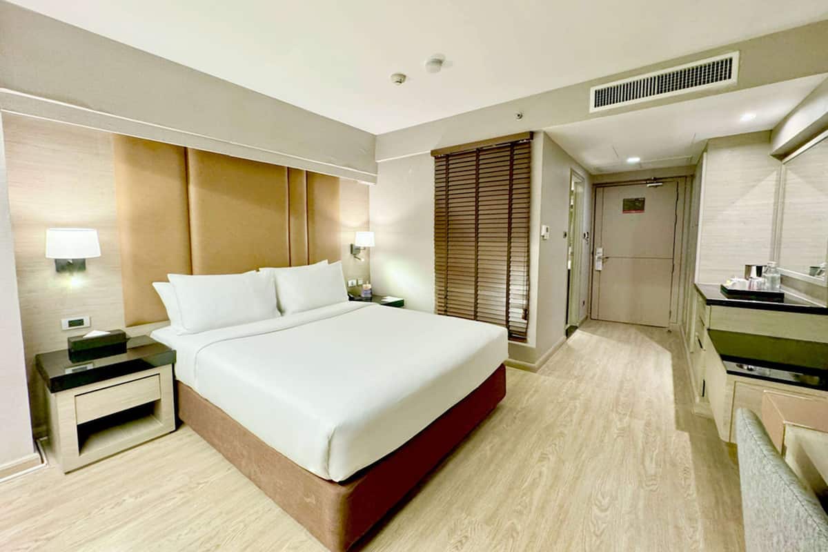 Habitación de hotel con una cama grande, mesitas de noche, un escritorio y una kitchenette.