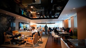 Un restaurant moderne doté d’un bar, d’un sol en bois et proposant différents types de sièges, notamment des tables et des chaises.