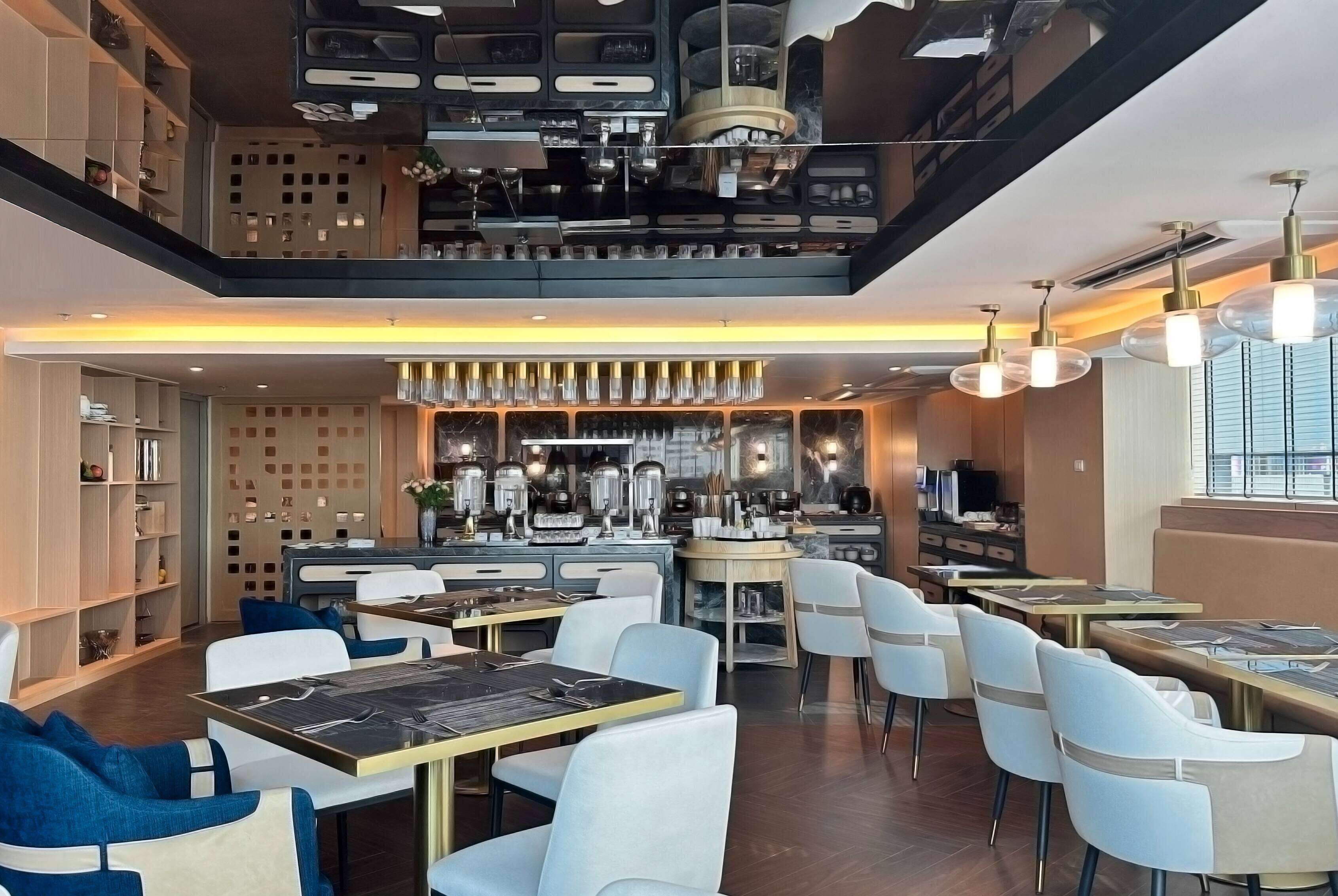 Un restaurant moderne doté d’un bar, de tables et de chaises, et d’une cuisine située à l’arrière.
