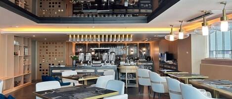 Un restaurant moderne doté d’un bar, de tables et de chaises, et d’une cuisine située à l’arrière.