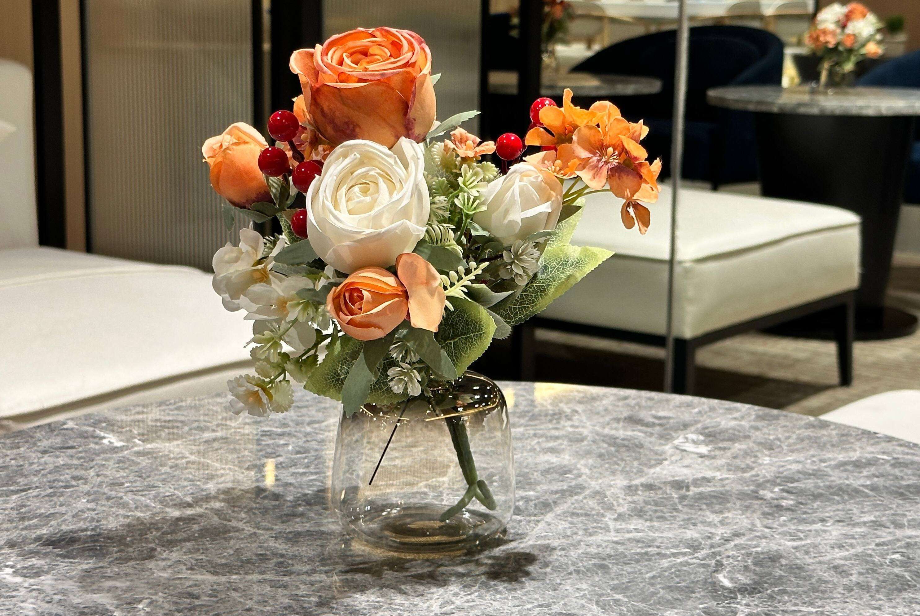 A marble table with a clear glass vase containing a bouquet of flowers.