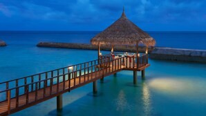 A wooden pier leading to a thatched-roof structure over water. - Ellaidhoo Maldives by Cinnamon (Ellaidhoo)