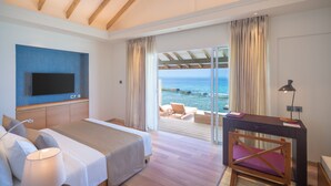 A hotel room with a bed, a desk, a TV, and a balcony with a view of the sea. - Ellaidhoo Maldives by Cinnamon (Ellaidhoo)