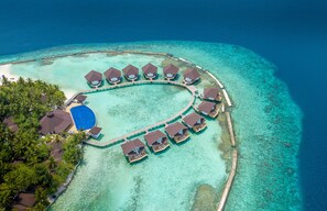 An aerial view of a resort with overwater bungalows arranged in a semi-circle around a central pool, connected by walkways. - Ellaidhoo Maldives by Cinnamon (Ellaidhoo)