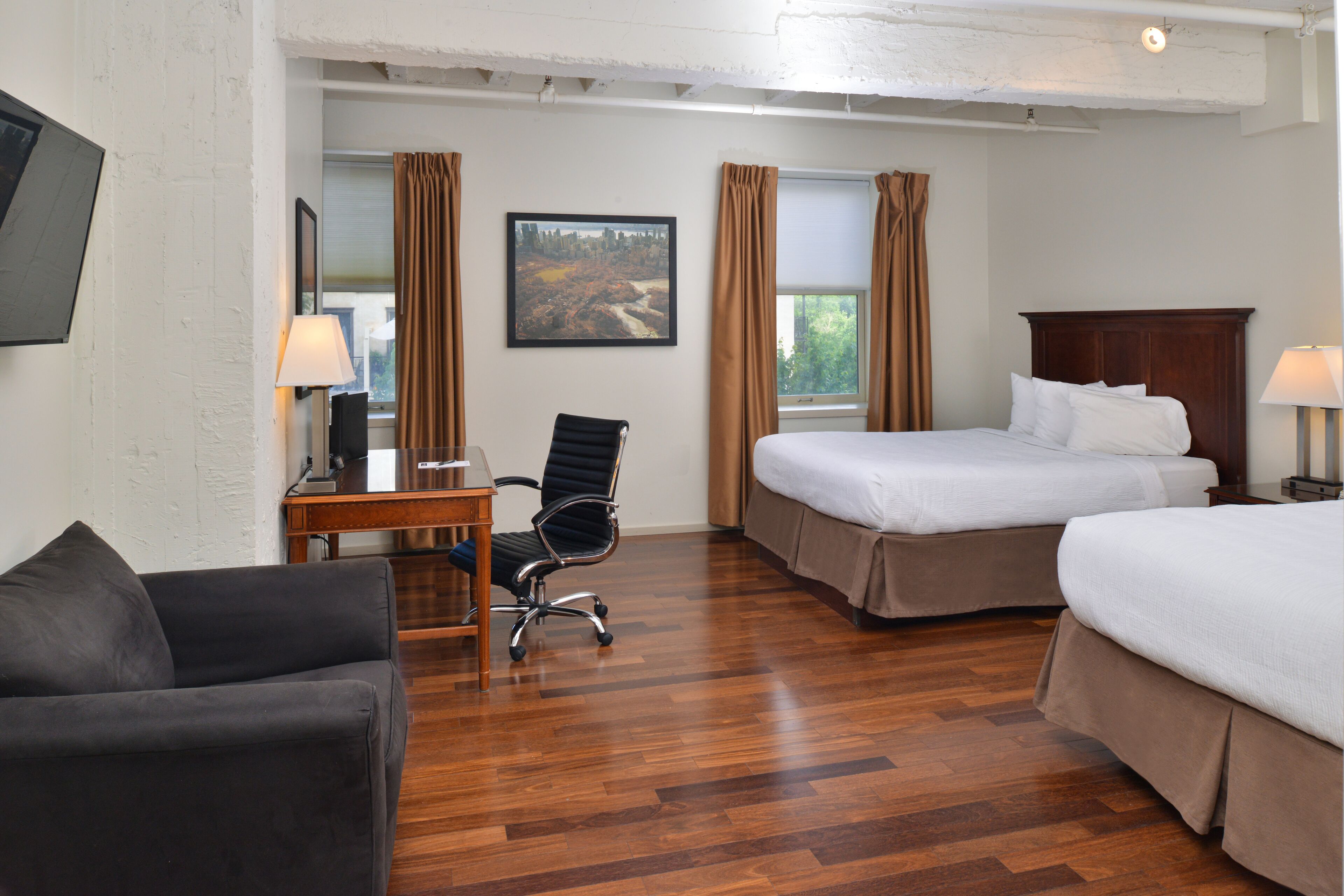Habitación de hotel con dos camas, un escritorio, una silla y un sofá.