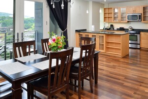 Una cocina moderna con armarios de madera, un horno de acero inoxidable y un comedor con mesa y sillas.