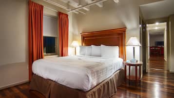 A hotel room with a large bed, two bedside lamps, a wooden headboard, and a window with curtains.