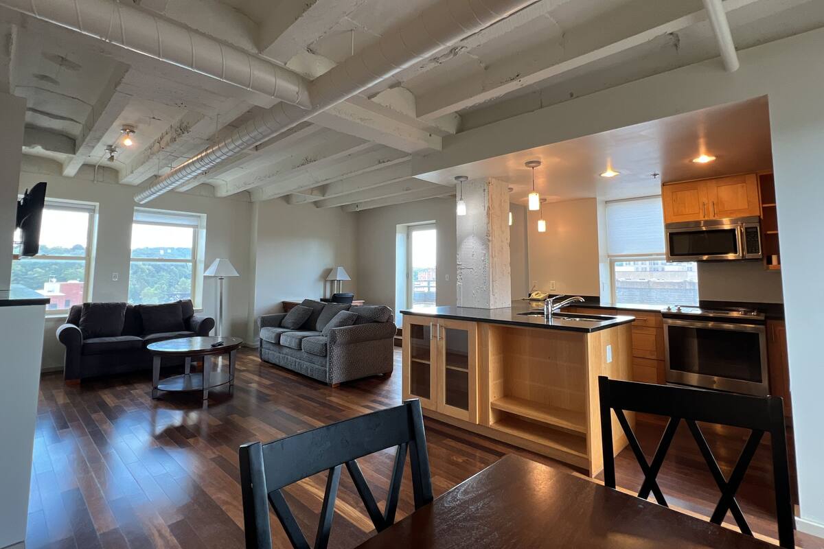 A modern kitchen with stainless steel appliances, a wooden dining area, and a cozy living space with a sofa and coffee table.