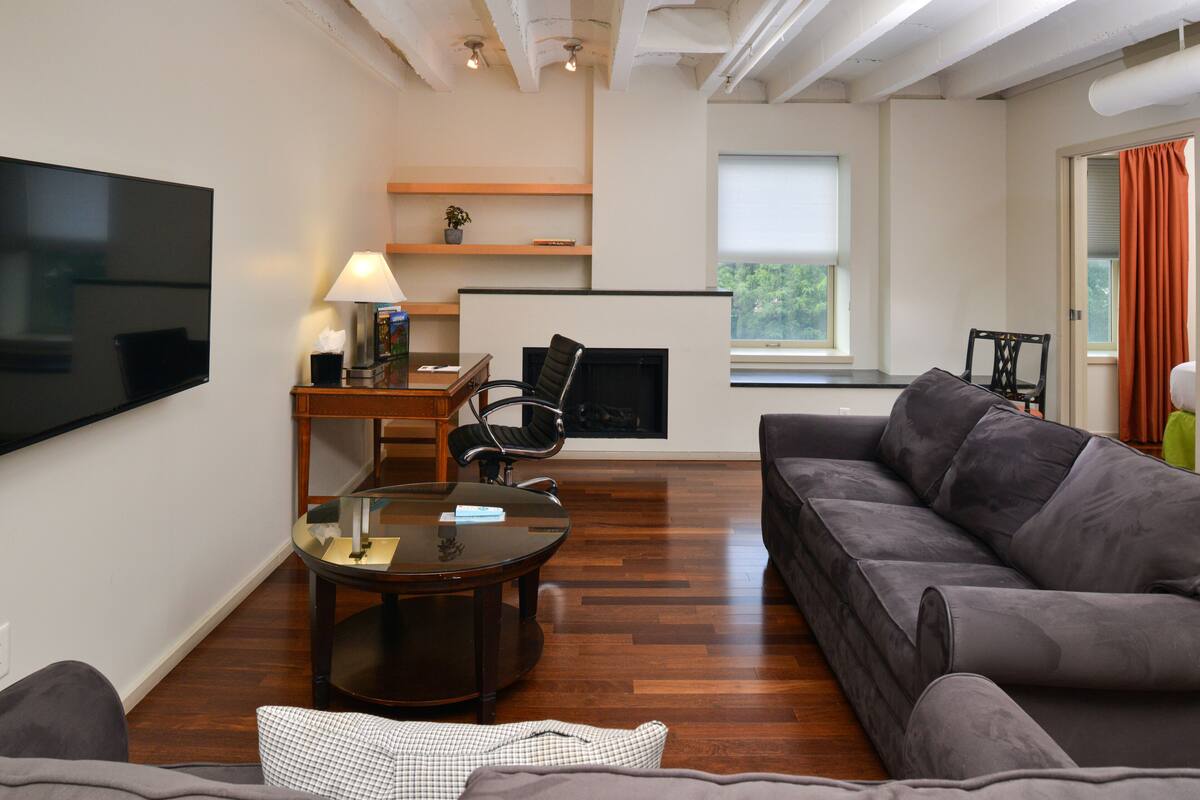 A modern living room with a flat-screen TV, a sofa, a coffee table, and a fireplace.