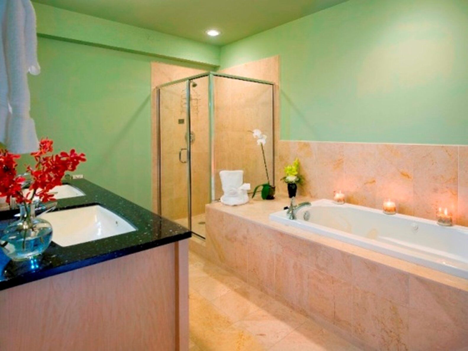 A bathroom with a glass-enclosed shower, a bathtub, and a sink with a vase of flowers.