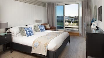Un dormitorio con una cama grande, una mesita de noche, una silla, un escritorio y vistas al exterior a través de una puerta corredera.