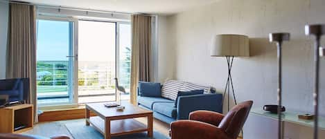 Een moderne hotelkamer met een balkon, een bank, een bijzettafeltje en lederen stoelen.