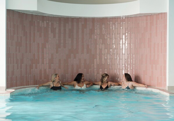 Una piscina con pared de azulejos rosa y techo curvo.