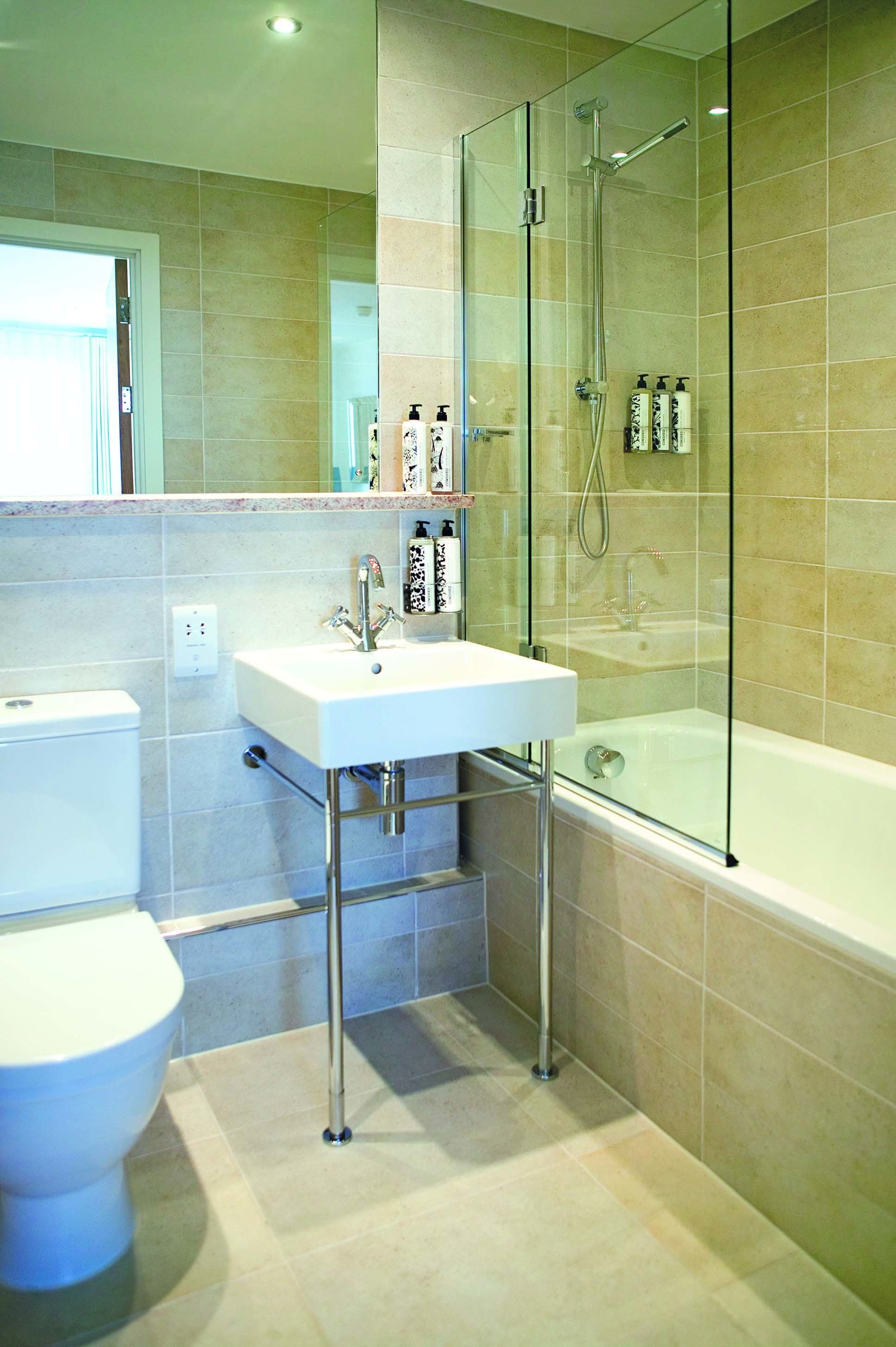 A modern bathroom with a glass-enclosed shower, a white sink, and a toilet.