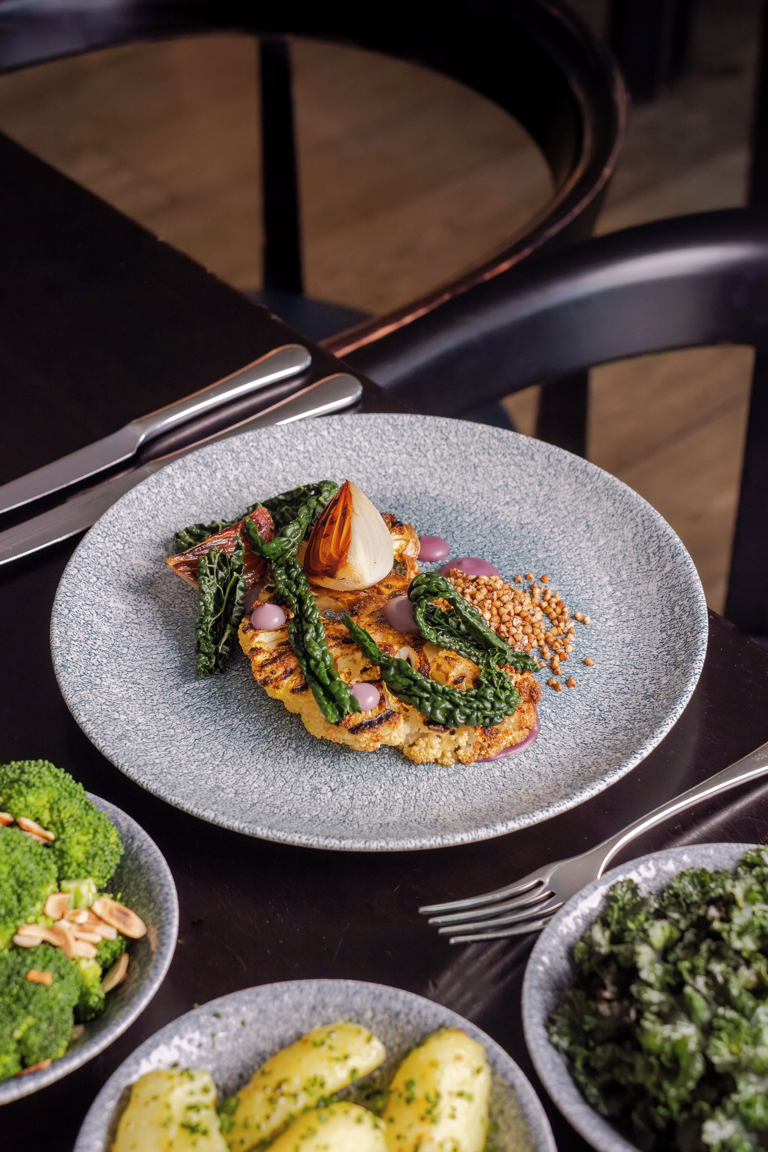A dining table with a plate of food, a fork, and a knife.