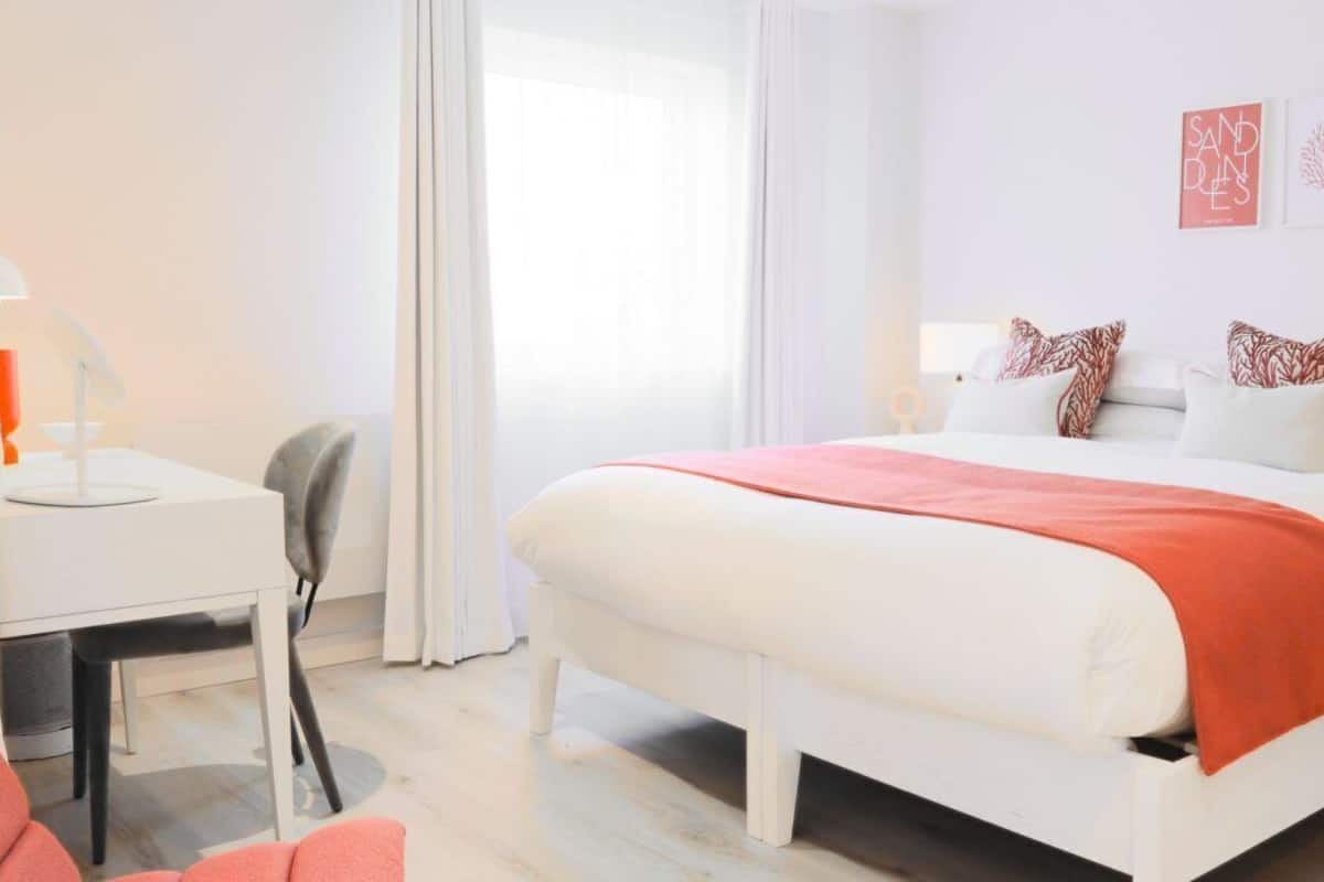 Una habitación de hotel con cama, mesitas de noche, escritorio y silla.