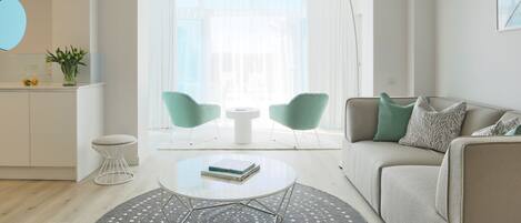 A modern living room with a sofa, two chairs, a coffee table, and a dining table.