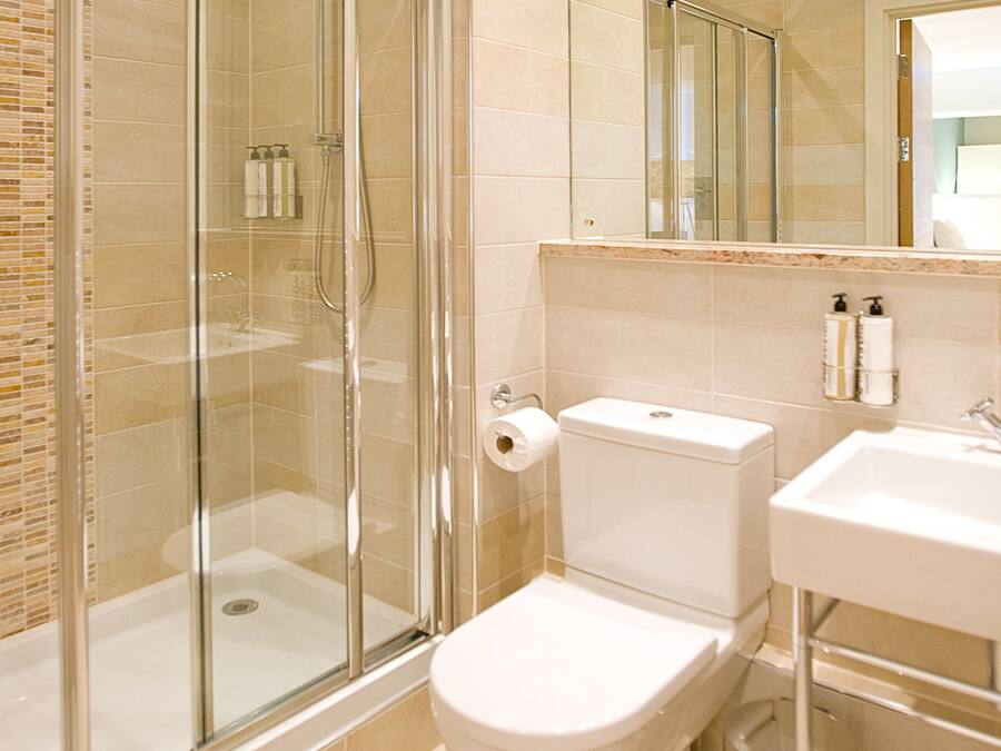Ein modernes Badezimmer mit einer Duschkabine, einer Toilette, einem Waschbecken und einem Spiegel.