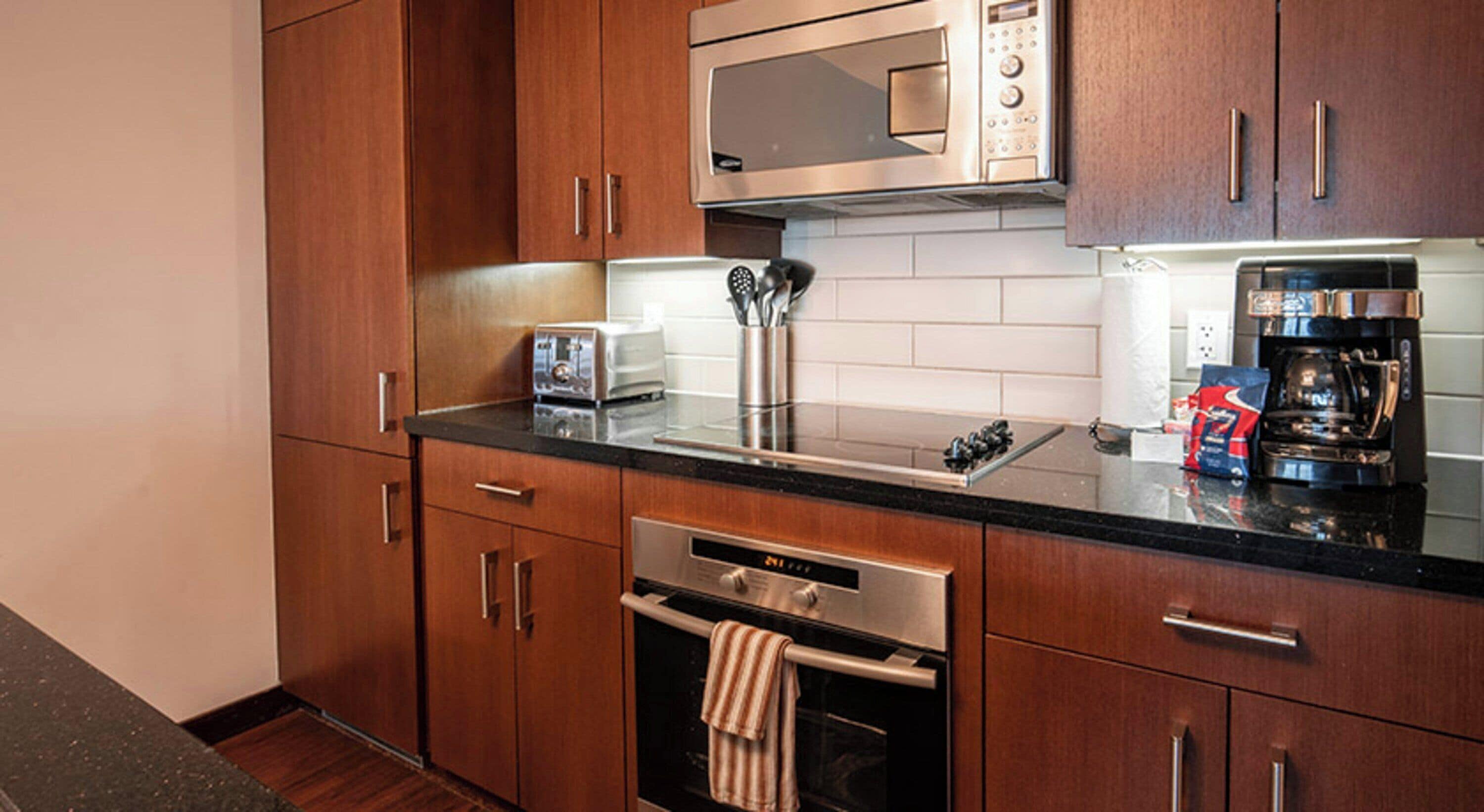 A modern kitchen with wooden cabinets, stainless steel appliances, a microwave, a toaster, and a coffee maker.