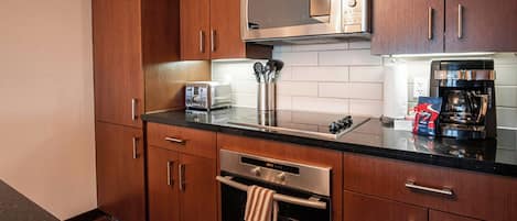 Una cocina moderna con armarios de madera, electrodomésticos de acero inoxidable, microondas, tostadora y cafetera.