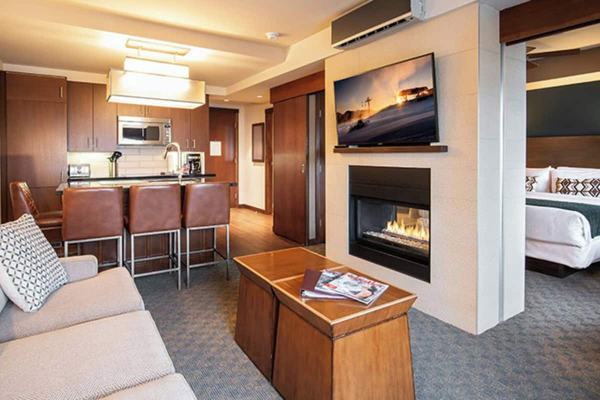 Habitación de hotel con sala de estar, kitchenette y chimenea.