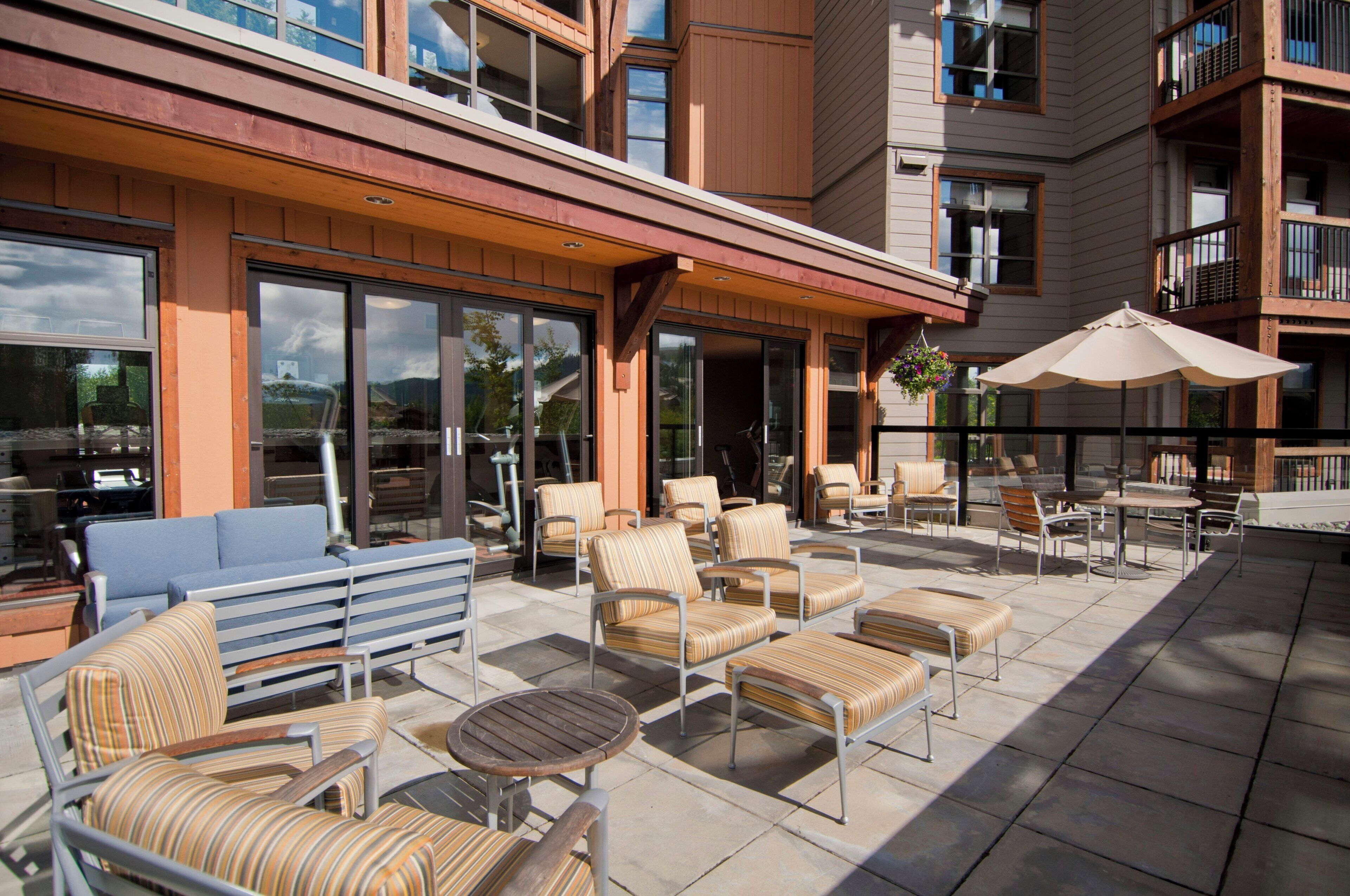 An outdoor patio with multiple seating areas, including sofas and chairs, and a table.