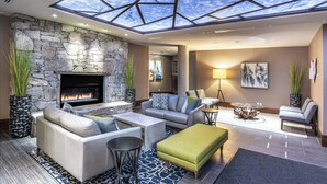 Un salon moderne avec une cheminée en pierre, des sièges confortables et une lucarne.
