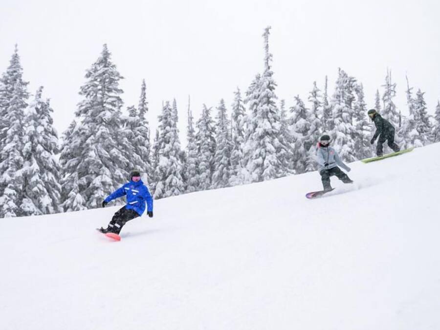 A snowy slope with snowboarders.