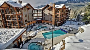 Un chalet à plusieurs étages doté d’un espace piscine, entouré d’un paysage enneigé et de montagnes.