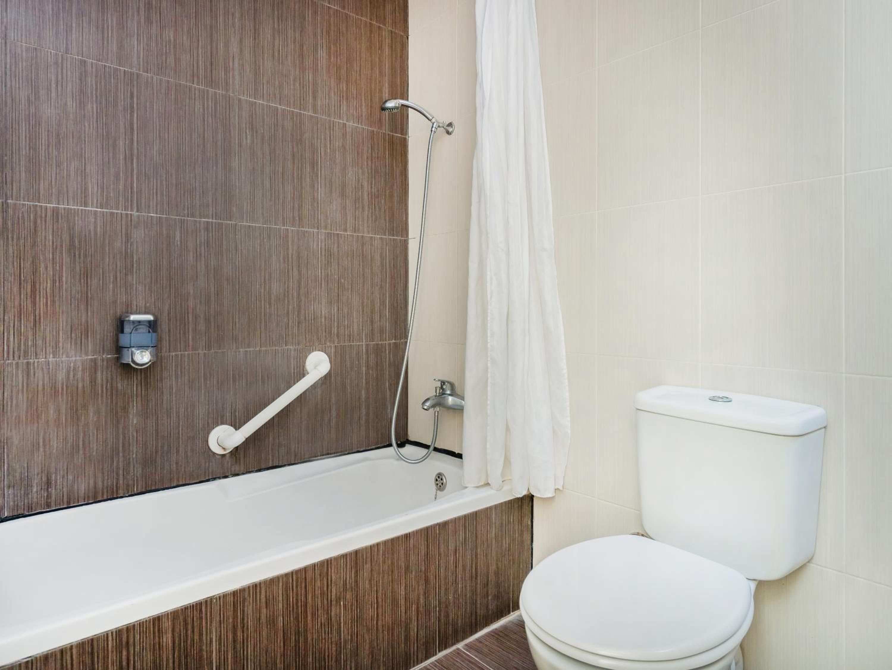 Un baño con tocador de madera, inodoro blanco y zona de ducha.