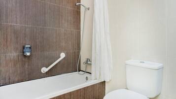 Un baño con tocador de madera, inodoro blanco y zona de ducha.