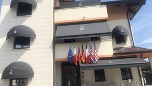Un hotel con varios balcones, una fila de banderas y mobiliario para exteriores.