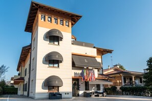 A hotel with a prominent 'HOTEL' sign, multiple balconies, and flags. - Small Hotel Royal (Padova)