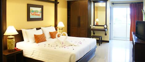 A hotel room with a large bed, two bedside tables with lamps, a wardrobe, a mirror, and a television.