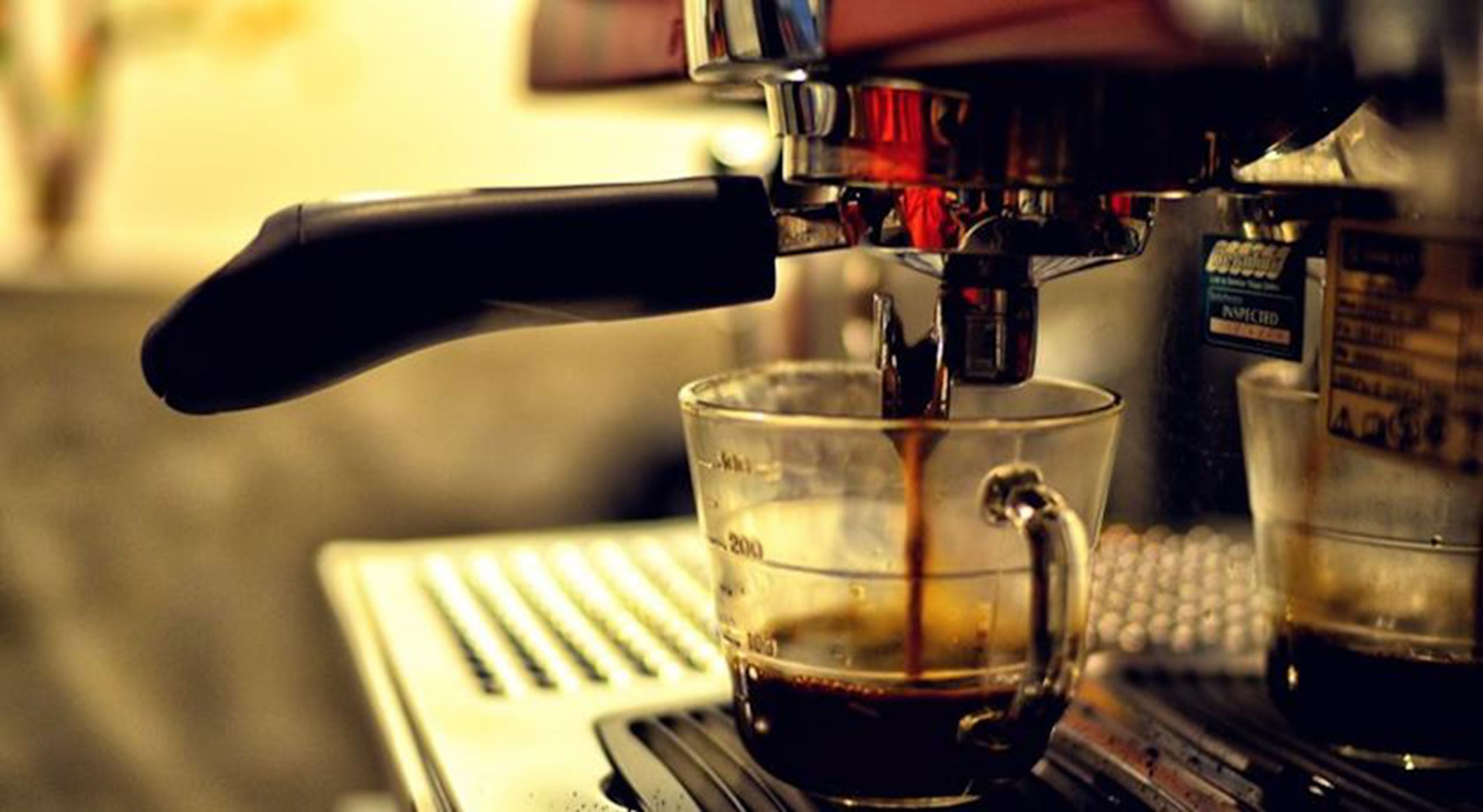 A coffee machine dispensing coffee into a glass cup.